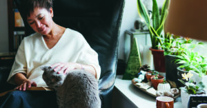 Senior Asian woman enjoying her time with pet while reading book.