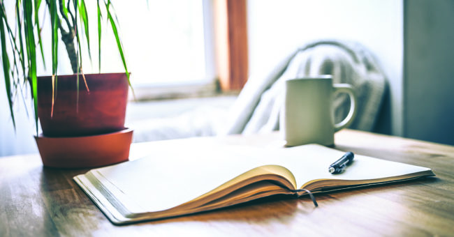 managing-negative-self-talk-featured-image An open journal and pen on a table with a cup of tea for a mental health break