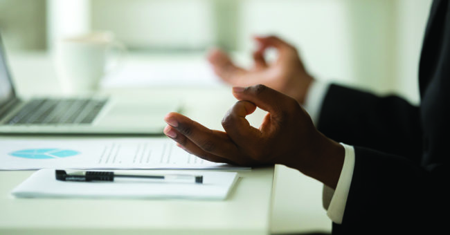 mindfulness-featured-image African-american businessman in suit meditating in office, close up view