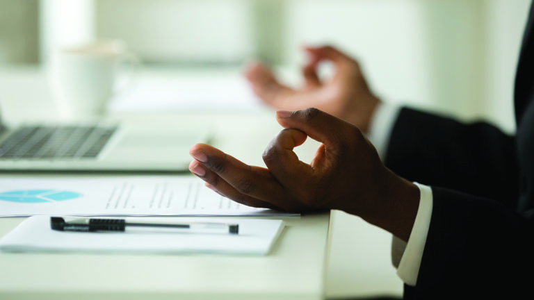 mindfulness-featured-image African-american businessman in suit meditating in office, close up view