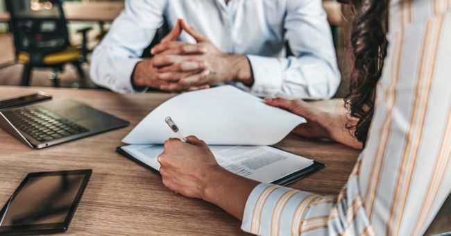 online-harassment-featured-image Female businessperson signs contract. Close up of female hand signing formal paper on the office table