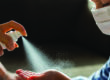 Unrecognizable single parent spraying hand sanitizer to her little boy's hand. Boy is with face mask.