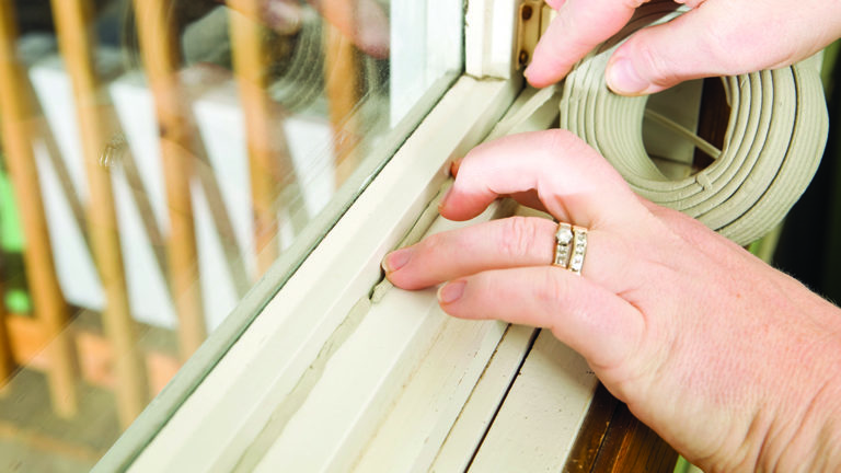 reducing-summer-cooling-costs-featured-image Hands Applying Weather Seal Caulk to Window Frame