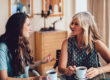 Older mother and daughter spending time together at home drinking coffee and discussing