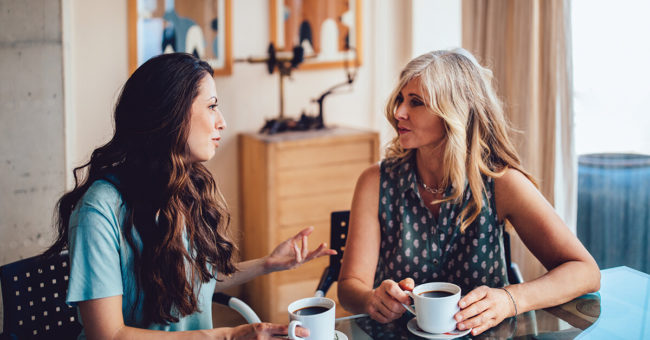 second-anniversary-covid-featured-image Older mother and daughter spending time together at home drinking coffee and discussing