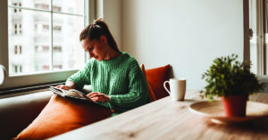 Female Looking At Old Photo Album In Home Kitchen