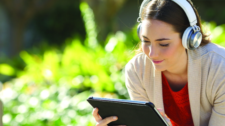 sound-bathing-featured-image Woman wearing headphones watching media on tablet in a park