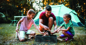 Father and daughters camping in beautiful nature